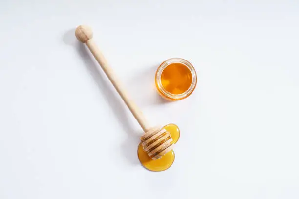 honey dipper and honey jar on white background