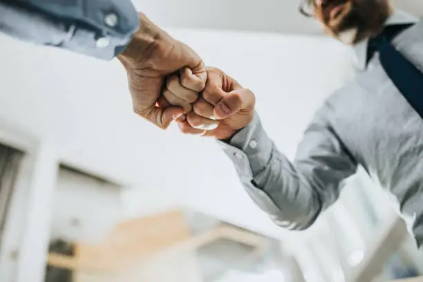 Close up of two unrecognizable businessmen greeting each other with fist bump.