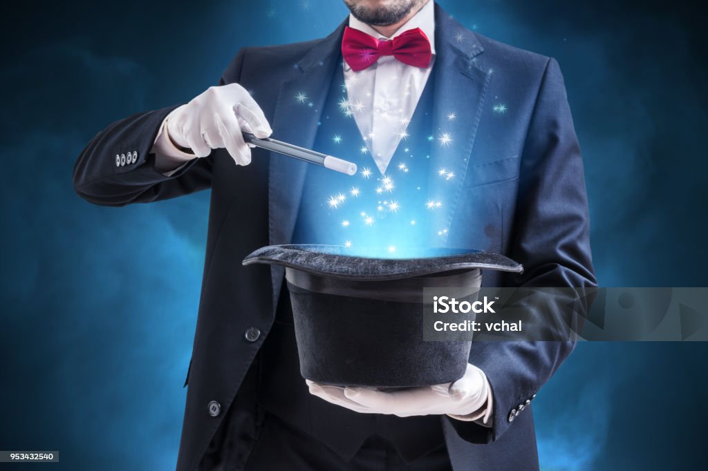 Magician or illusionist is showing magic trick. Blue stage light in background. Magician Stock Photo