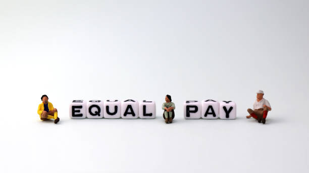 istock An equal pay concept. EQUAL PAY text cube and three miniature people. 953433286
