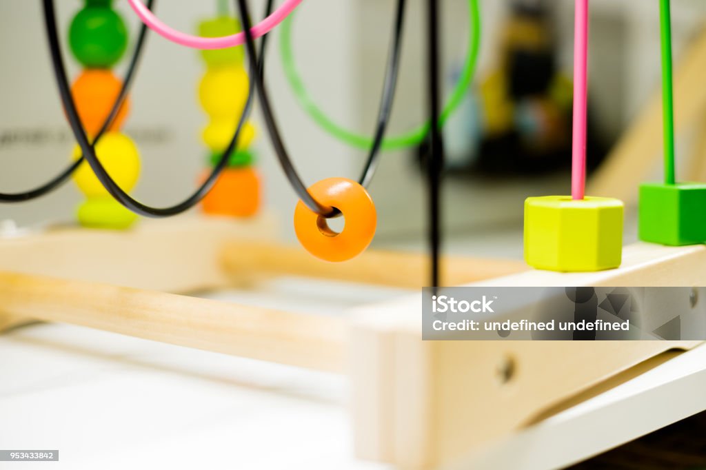 Wire bead maze standing on a table. Kid activities.Colorful Educational Toy.Wooden Wire Maze Educational Game Toys Wire bead maze standing on a table in front of the window with bright toy cars in the foreground. Kid activities Bead Stock Photo