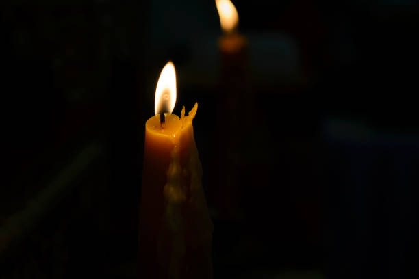istock One yellow candle burning brightly in black background 953442666