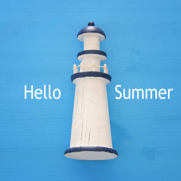 istock vacation and summer image with lighthouse over blue wooden background. 953445150