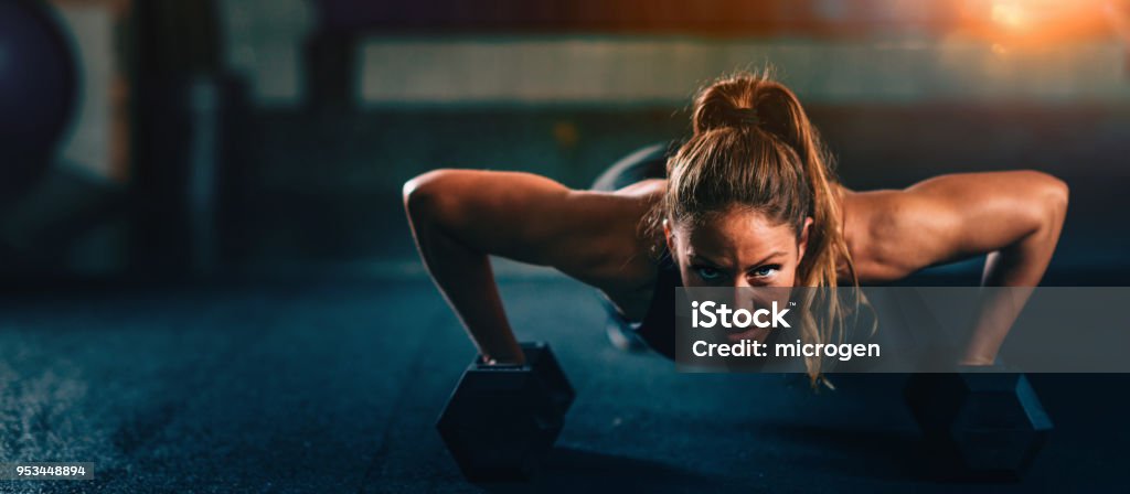 Cross training fitness. Young woman exercising Cross training fitness. Young woman doing pushups with dumbbells. Panoramic image, convenient copy space Exercising Stock Photo