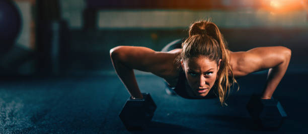 Cross training fitness. Young woman exercising Cross training fitness. Young woman doing pushups with dumbbells. Panoramic image, convenient copy space bodyweight training photos stock pictures, royalty-free photos & images