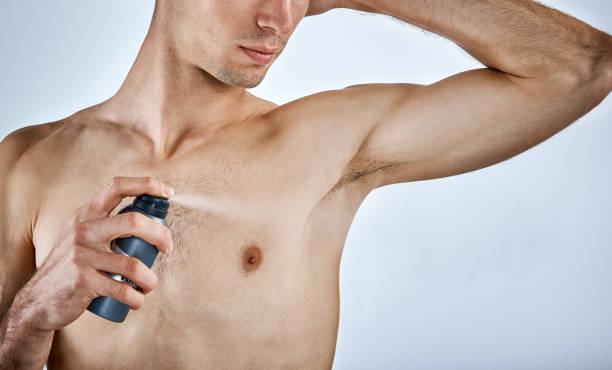 istock Muscular young man sprays armpit with deodorant 953453742