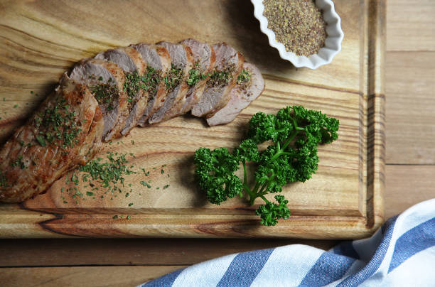 slice of roasted pork loin with organic parsley and flaxseed powder on wooden cutting board - roasted spit roasted roast pork barbecue grill imagens e fotografias de stock