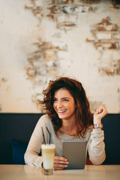 istock Young caucasian woman using tablet while sitting in cafe and drinking coffee. 953459734