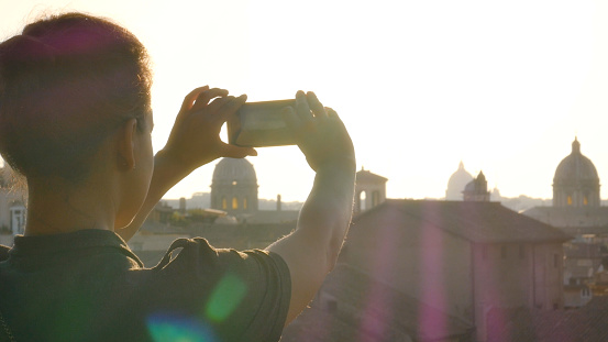 Young woman in campidoglio balcony takes pictures of rome's cityscape