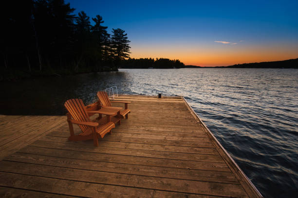istock Two Adirondack chairs sitting on a wooden dock at sunset 953465104