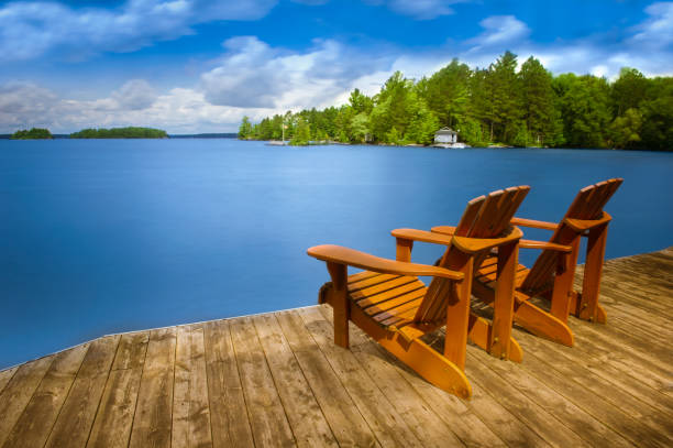 Two Adirondack chairs sitting on a wooden dock stock photo