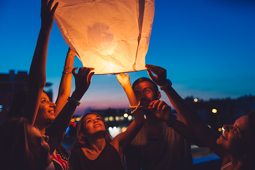 Happy friends holding a burning lantern ready to fly in the sky