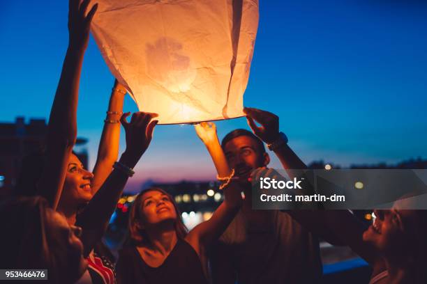 Friends On Rooftop Party Releasing Paper Lantern Stock Photo - Download Image Now - Hot Air Balloon, Releasing, Lantern