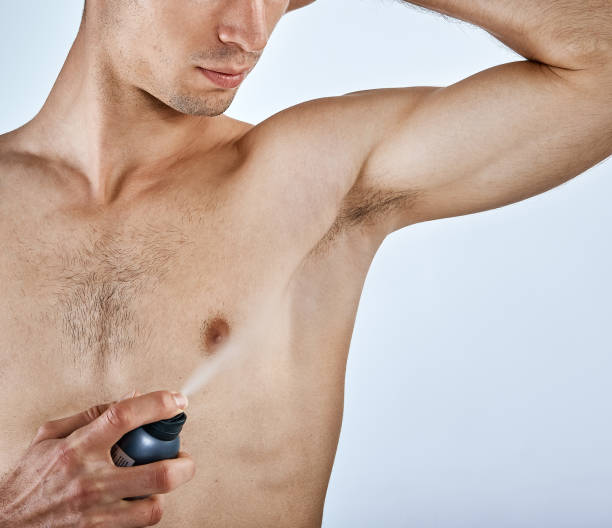 istock Muscular young man sprays armpit with deodorant 953467434