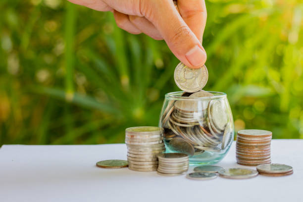 istock Hand of  female putting coins in jar with money stack step growing growth saving money 953469822