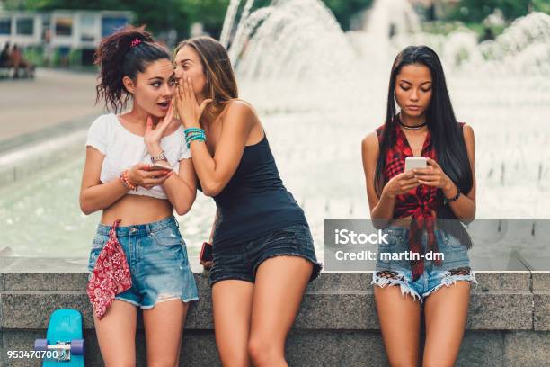 Young Woman Telling A Secret To A Friend Stock Photo - Download Image Now - Gossip, Whispering, Speaking with Forked Tongue