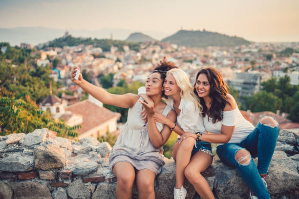 Women taking selfies against the cityscape Happy friends taking photos on the mountain top girlfriend stock pictures, royalty-free photos & images