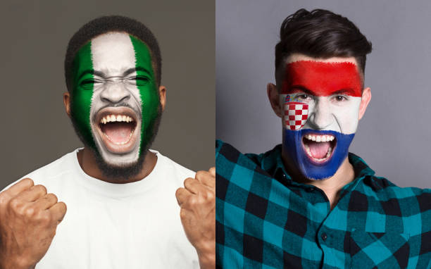 istock Emotional soccer fans with painted flags on faces 953471308