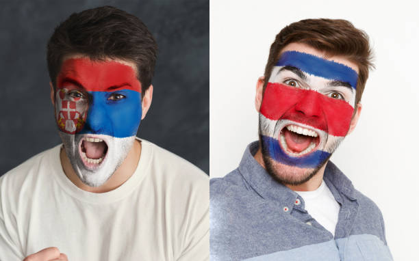 istock Emotional soccer fans with painted flags on faces 953472098