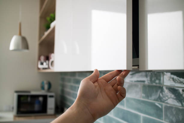 istock Kitchen interior with modern furniture. The man opens a modern hanging cabinet for a kitchen without door handles 953474296