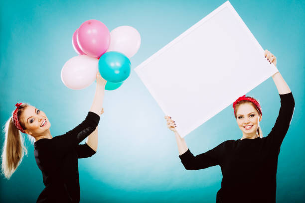 istock Two girls with blank board and balloons 953474782