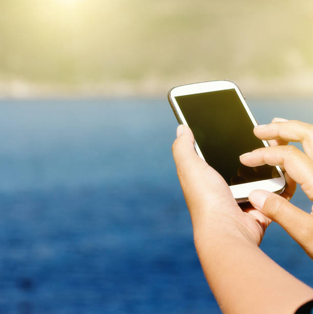 istock Female hands use a smart phone at the seaside 953475612