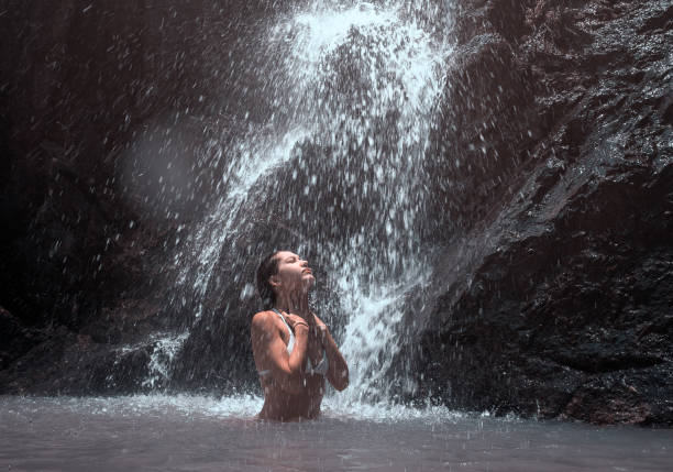 Beautiful young woman enjoy a waterfall. stock photo
