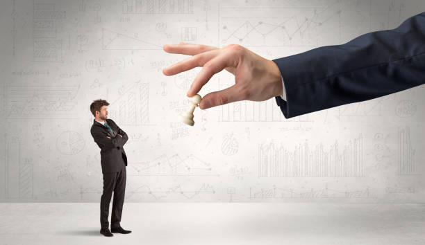istock Businessman is afraid to make the next step in a chess game with graphs background 953507270