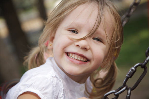 A young girl happily rides her bright pink bicycle around a lively playground that is filled with colorful toys all around