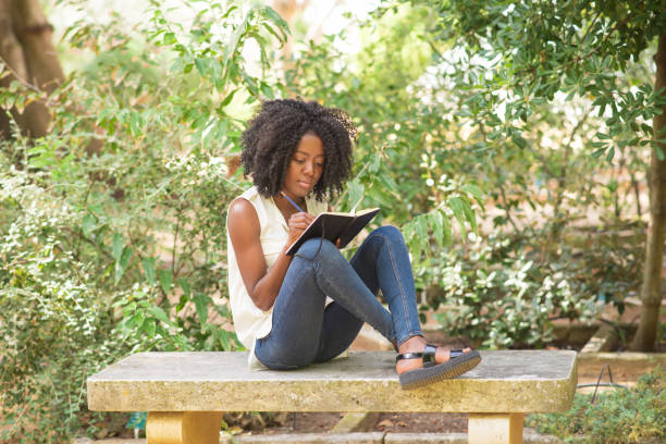 istock Content young attractive black woman making notes in park 953511964