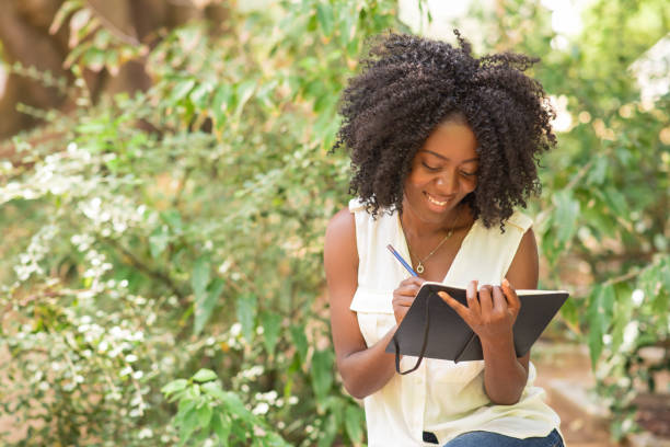 istock Happy young attractive black woman making notes in park 953511990
