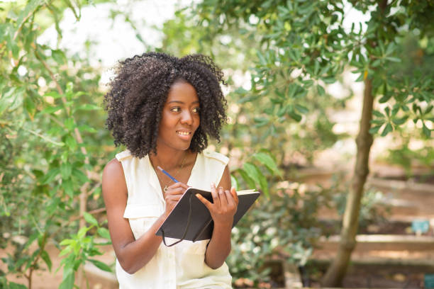 istock Pensive young attractive black woman making notes in park 953512204