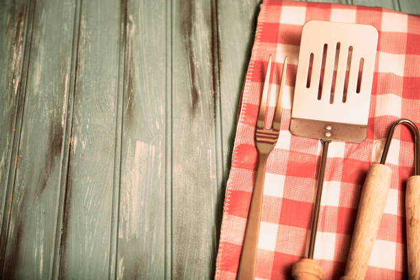istock Outdoor grilling, BBQ utensils on rustic picnic table. 953512746