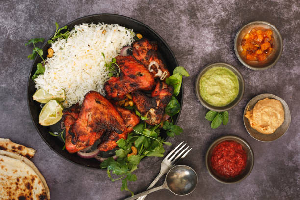 Indian Tandoori Chicken Wings And Sauces Tandoori chicken wings with spicy pilau rice, lime and traditional assortment of sauces on rustic table, top view indian food stock pictures, royalty-free photos & images