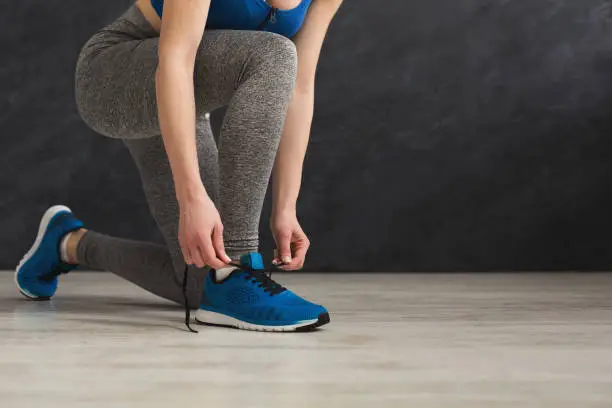 Photo of Woman tying up lace on sport shoes closeup