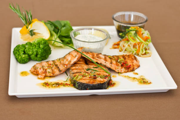 стейки из лосося, на гриле. подается с овощами и специями на белой тарелке - main course salmon meal course стоковые фото и изображения