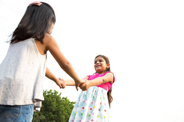 Two young girls hold hands and spin around on an empty parking lot
