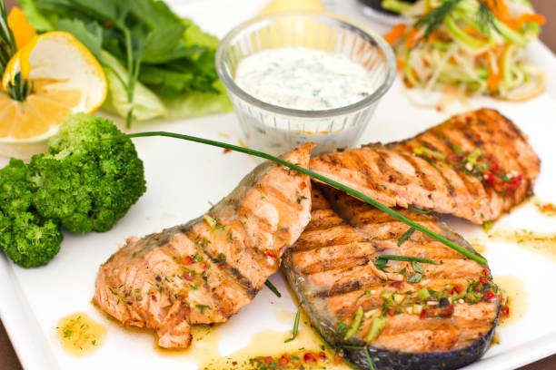 steaks of salmon, grilled. served with vegetables and spices on the white plate - main course salmon meal course imagens e fotografias de stock
