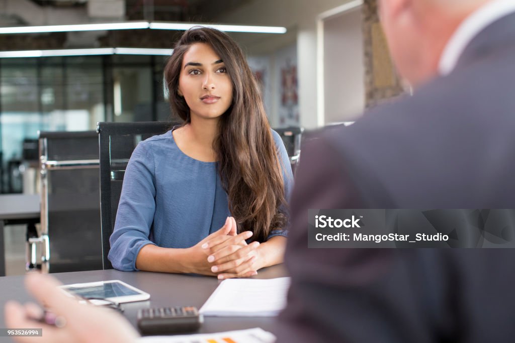 Focused Indian female customer meeting with financial advisor Focused Indian female customer meeting with financial advisor. Young beautiful candidate at job interview in modern office space. Business consulting or employment concept India Stock Photo