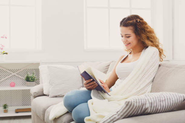 istock Cozy home. Young thoughtful woman with book 953528646