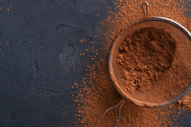istock Sifted cocoa powder in a sieve over black background 953530782