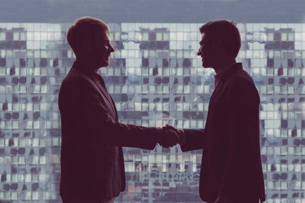 istock Silhouettes of Businessmen Shaking Hands 953534844
