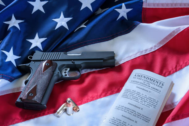 istock The second amendment and gun control in the US, concept. A handgun, bullets, and the american constitution on the USA flag. 953547342