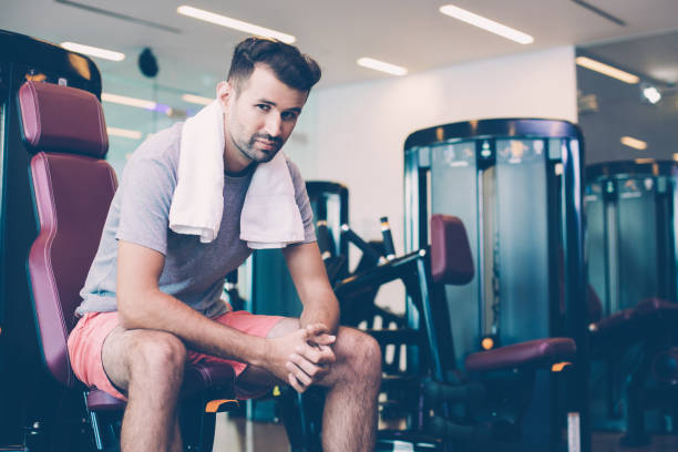 istock Tired young man relaxing on weight machine in gym 953553456