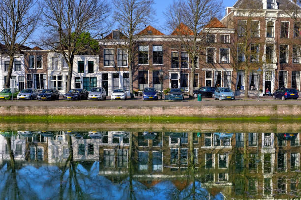 Zierikzee, Zeeland,Netherlnds - April 19, 2018: Dutch row houses ,trees and cars parked along the quay,reflected in the water of the inner harbor in the old historic town of Zierikzee.