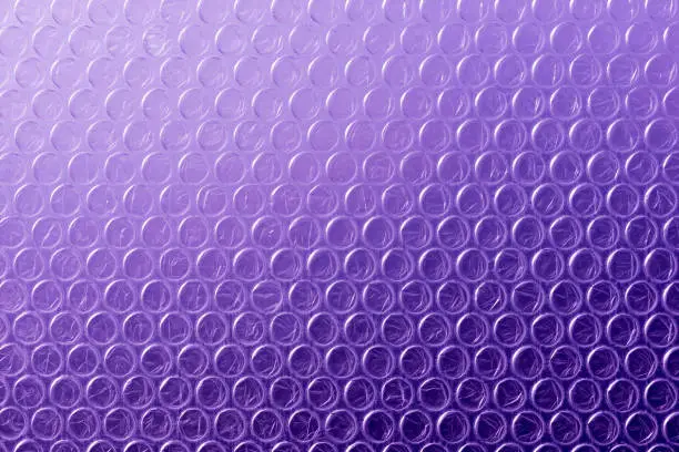 Full frame plastic bubble wrap abstract background image in ultra violet purple colour.