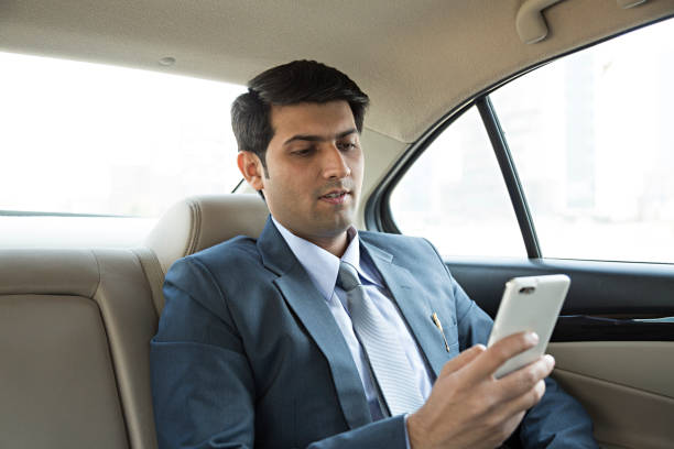istock Man sitting in car and texting on the phone - Stock image 953587268
