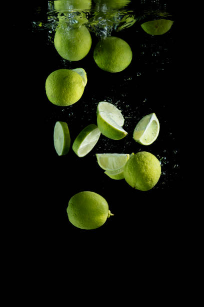 Fresh limes are dropped into water.