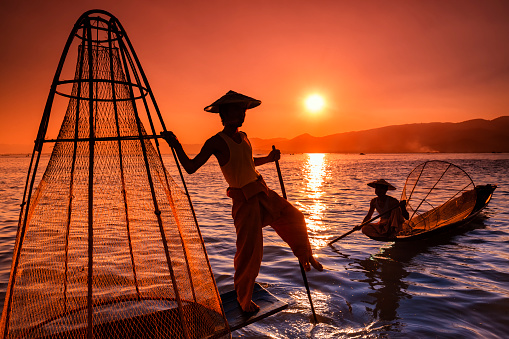 Fisherman on Inle Lake watching the sunset. Leg-rowing fishermen on Inle Lake are a major tourist destination in Myanmar (Burma).