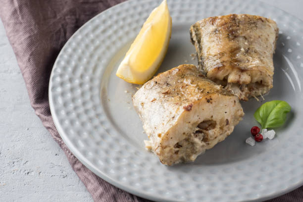 baked pollock fish with lemon and spices on a plate napkin on the table - pollock trawler imagens e fotografias de stock